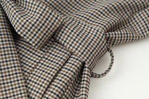Detailed view of houndstooth plaid fabric texture and waist buckle sewing on the blazer set