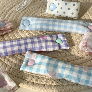 Close-up of fabric cable organizers in plaid and polka dot patterns with heart-shaped buttons