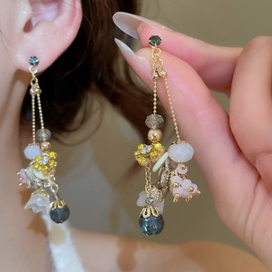 Macro view of crystal flower drop earrings with blue crystals and gold chain details