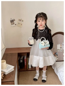 Close-up of a child model holding a light blue houndstooth bow mini handbag for girls