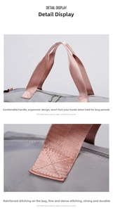 Detail of gray travel bag featuring pink reinforced handles and ergonomic cross stitching