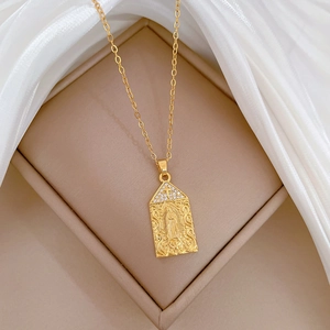 Detailed close-up of golden Virgin Mary pendant with cross on a soft silk background