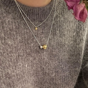 Close-up of minimalist layered double silver and gold ball necklace on a model