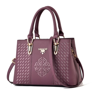Purple embroidered tote bag with woven texture and gold hardware on white background