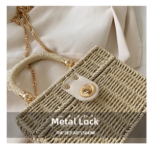 Detailansicht der Strohtasche mit goldenem Drehverschluss und eleganter Kette