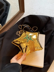Gold star evening bag featuring rhinestones and tassel details on a black blazer background