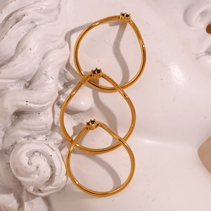 Three thin 18K gold plated V-shaped rings with black gemstones on a white sculpture