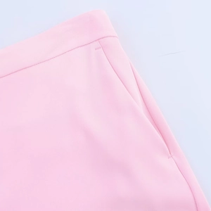 Vue détaillée du pantalon de tailleur rose montrant le tissu tissé et la poche latérale