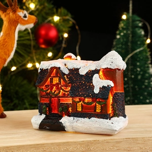 Close-up of lighted resin Christmas house with snow decor and festive wreaths