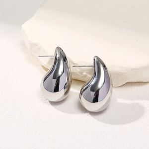 Macro shot of silver teardrop earrings with a polished metallic finish on white stones