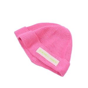 Detail der rose-pinken Strickmütze mit Rippenmuster und neonfarbenem Buchstaben-Aufnäher