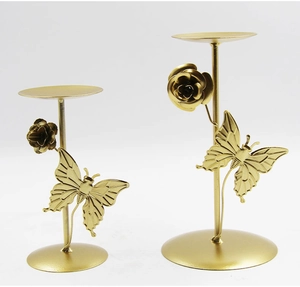 Detail of golden metal candle holders with decorative butterflies and roses on white background