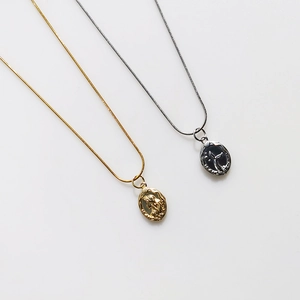 Double-sided mermaid relief pendant necklace in gold and silver finish on white background
