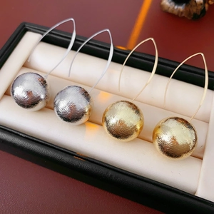 Gros plan de boucles d'oreilles boules en métal brossé or et argent sur boîte noire