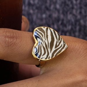 Macro shot of 18K gold plated heart ring with zebra print pattern on finger