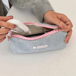 Detail of light blue denim stationery pouch with embroidery and zipper closure