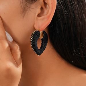 Close-up of a black velvet wrapped heart hoop earring with gold beads on a model's ear