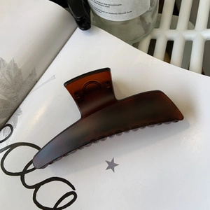 Macro detail of a large amber resin hair claw clip resting on minimalist white books