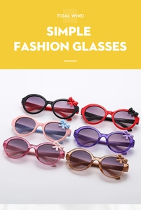 Detailed close-up of colorful round frame kids sunglasses with bow accents on the side