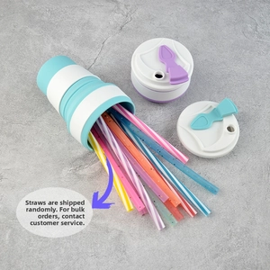 Collapsible silicone travel cup with colorful straws and lids on grey stone background