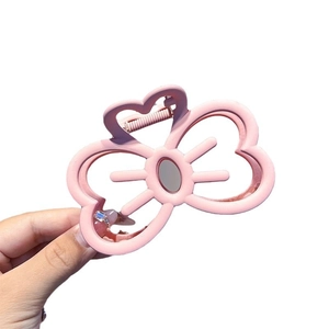 Pink matte kitten-shaped hair claw clip with bow and hollow design held in hand