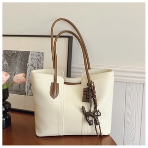 Detailed view of cream PU leather tote bag with brown straps and cute cat charms