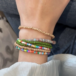 Close-up of bohemian multilayer seed bead bracelets worn on wrist with colorful accents