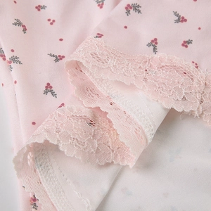 Détail macro du tissu rose à fleurs avec une bordure en dentelle large et exquise