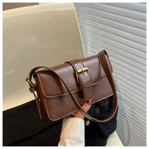 Detail of vintage brown shoulder bag featuring a golden metal buckle and leather texture