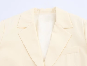 Detailed view of the peak lapel and fabric texture on a cream longline blazer