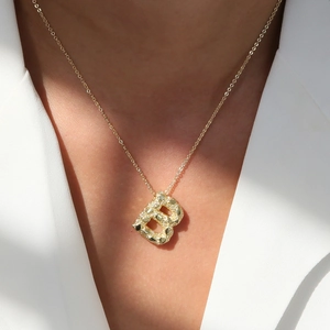 Golden balloon texture letter B pendant necklace on elegant woman in white suit