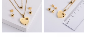Detailansicht der goldenen Herz-Halskette und Ohrringe mit Lineal zur Größenmessung