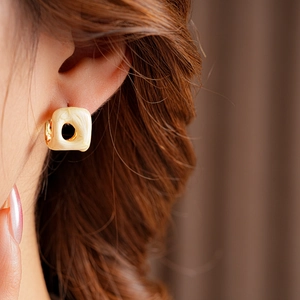 Close-up of French vintage gold square hollow earrings with cream enamel on model