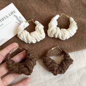 Détail de la texture tricotée et du fermoir doré sur ces boucles d'oreilles chic