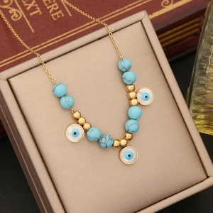Gold chain necklace featuring blue turquoise beads and evil eye charms on a jewelry box