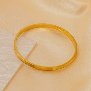 Detail of gold titanium steel bangle with four parallel grooves on champagne silk