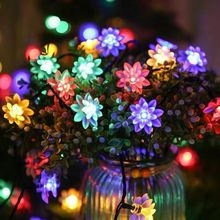 Close-up of lotus shaped solar LED fairy lights in glass jar with soft bokeh background
