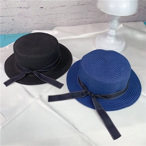 Detail of minimalist straw boater hats with bow ribbon on smooth silk fabric