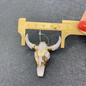 Detail view of acrylic bull skull pendant measured with brass caliper for size precision