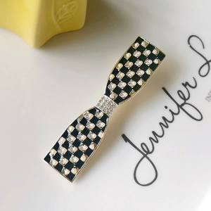 Detail of checkered hair clip with white pearls and sparkling rhinestones on metal base
