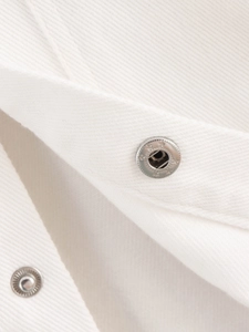 Macro view of white cotton twill fabric texture and silver star-engraved metal snap buttons