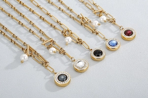 Detail of gold paperclip chain necklaces with colorful crystal pendants and pearls