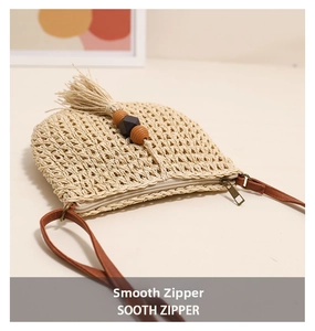 Detail of hand-woven straw crossbody bag with wooden beads tassel and smooth metal zipper