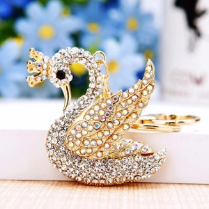 Close-up of sparkling swan keychain with crown and iridescent crystals on golden base