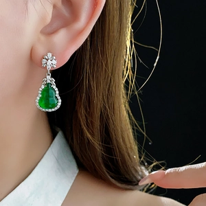 Close-up of model wearing green resin gourd earrings with white zircon accents