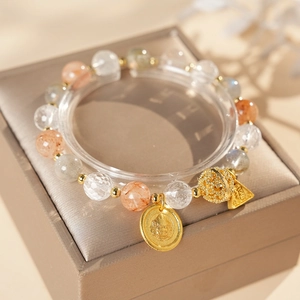 Detail of beaded gemstone bracelet with gold Buddha pendant and colorful crystals