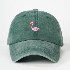 Close-up of pink flamingo embroidery on washed green cotton baseball cap fabric