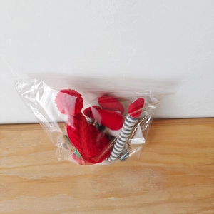 Détail de l'attache-rideau gnome en tricot rouge et gris sous emballage plastique