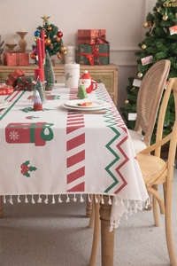 Close-up of Christmas table runner with festive gift patterns and white tassel fringe