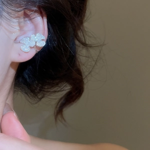 Detailed view of shimmering zircon flower ear cuff on ear with polished silver finish